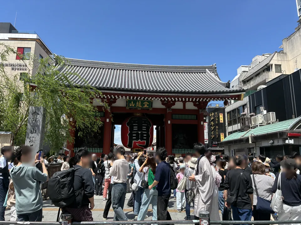 The Kaminarimon Gate (Thunder Gate) at Senso-ji in Asakusa surrounded by a dense festival-day crowd, showing the red gate with 金龍山 sign and large red 龍 (dragon)