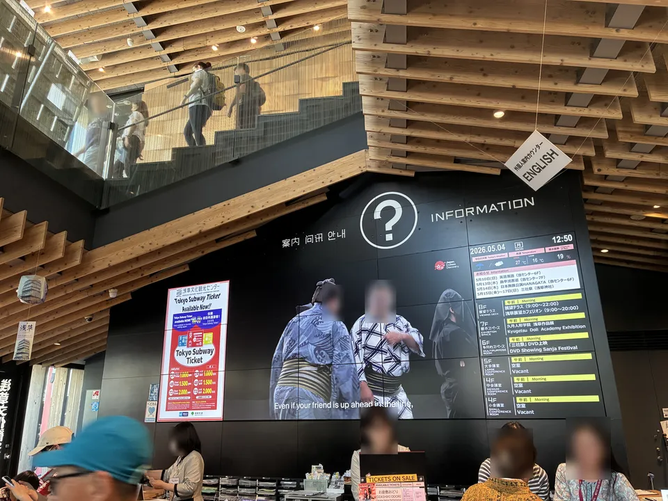 Interior of 浅草文化観光センター (Asakusa Culture Tourist Information Center) showing an INFORMATION screen with sumo wrestlers, a Tokyo Subway Ticket kiosk, date/time di