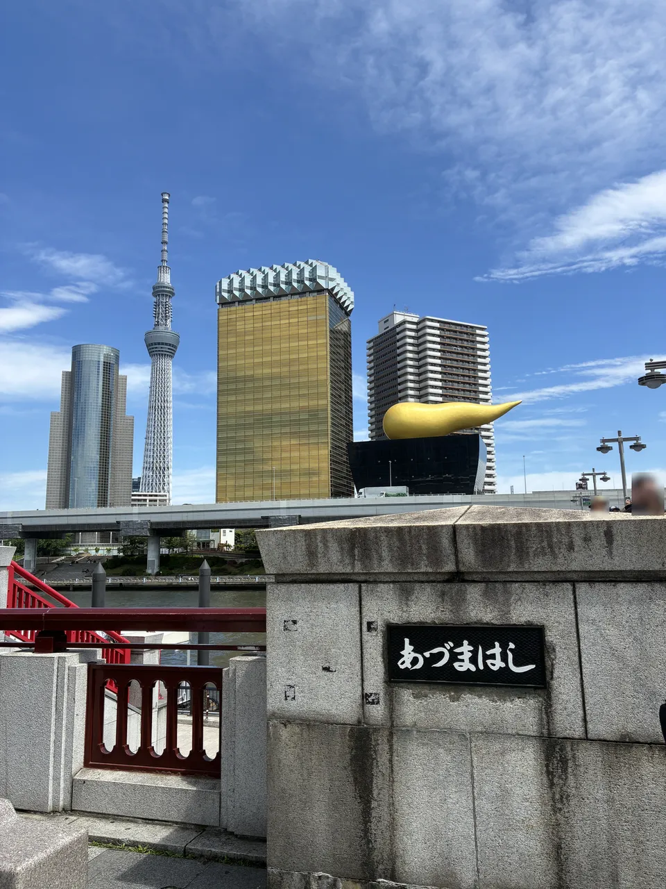 Rotated view from the あづまはし (Azumabashi) nameplate showing the Asahi Beer Tower with the gold Flamme d'Or sculpture, Tokyo Skytree rising at left, and the red b