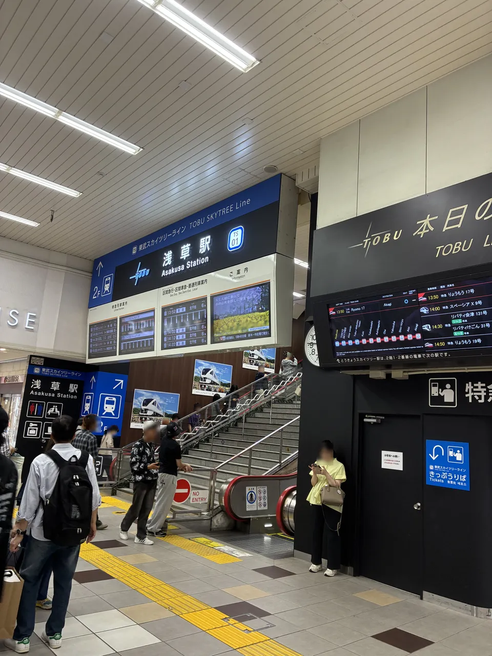 Tobu Asakusa Station hall with a blue TOBU SKYTREE Line Asakusa Station TS01 sign, an arrow to 2F, stairs and an escalator, and a limited express departure board
