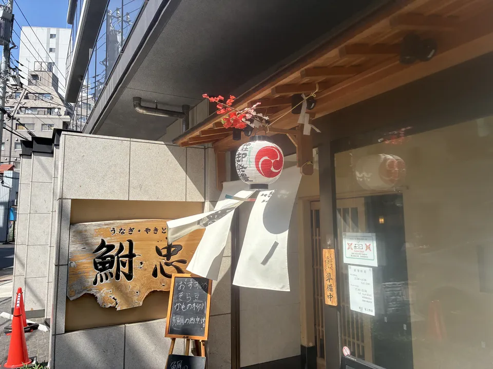 Entrance of Funachu (鮒忠) restaurant (うなぎ・やきとり) with a wooden sign board reading "鮒忠", a round red-and-white tomoe-pattern paper lantern hanging above, artificia