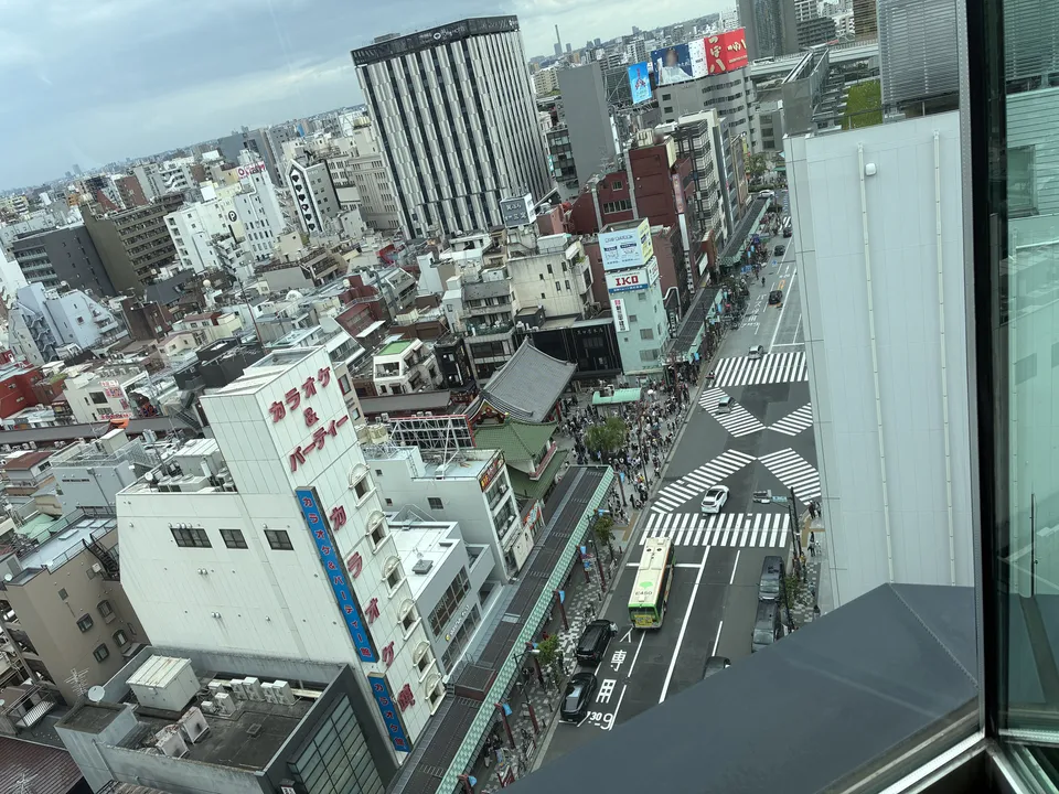 An aerial view of Asakusa below seen through floor-to-ceiling windows of The Gate Hotel Kaminarimon